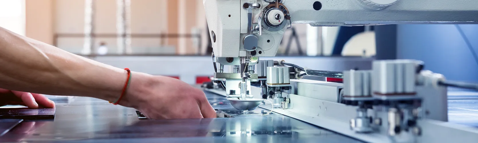 Mão a operar uma máquina de costura industrial na Rukom